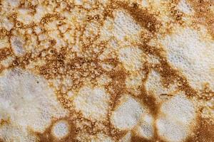 Pancake surface texture and pattern. Close-up of thin hot pancakes in a plate. Traditional rustic food. Graphic resource. photo