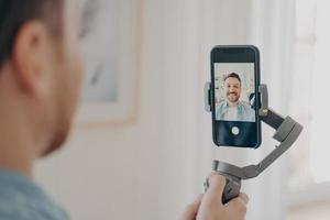 apuesto joven vlogueando o grabando video en un teléfono inteligente foto