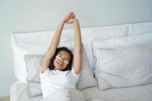 Young girl with moisturizing beauty under eye patches stretch in bed. Skincare, self-love, wellness photo