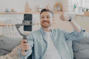 Young man in video call expressing his satisfaction by showing thumbs up photo