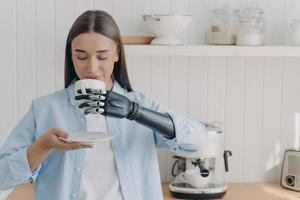 rutina de la persona discapacitada. una chica bastante discapacitada está sosteniendo una taza de té con la mano cibernética. foto