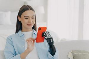 Happy european woman with bionic artificial arm chatting on smartphone. Innovation development. photo