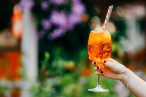 Outdoor shot of fresh cocktail with ice in womans hands against blurred background with copy space for your advertising content. Cold beverage for summer party photo