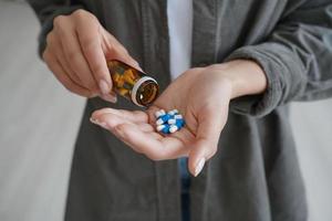 Drug addiction. Hand of african american girl or young woman holding medicine drugs and and flacon. photo