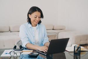 Happy woman is typing text on computer. Lady is chatting, having conversation with colleague. photo