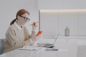 Lazy young woman is texting at workplace. Employee is distracting, surfing internet and having fun. photo