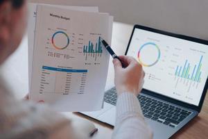 Financial round diagram on laptop screen and on paper. Man doing paperwork. Monthly budget planning. photo