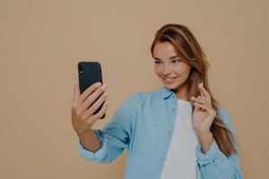 Pretty young woman makes selfie with smart phone photo