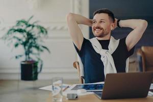 Happy businessman resting after work done at his cozy workplace in modern office photo