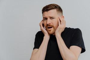 Shocked scared man looking at camera with frightened face expression photo