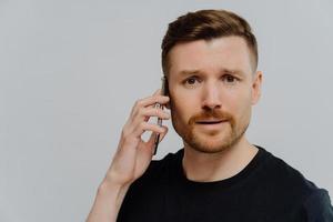 Worried man having unpleasant conversation on mobile phone and feeling unhappy photo