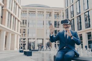 Impressed young businessman or office worker testing virtual reality goggles, using VR headset photo