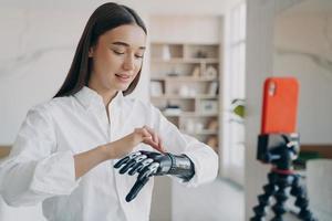 el amputado está tomando un video sobre cómo usar el brazo mioeléctrico de acero. linda chica discapacitada es bloguera. foto