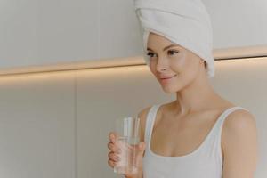 imagen de una mujer joven y hermosa con piel fresca y brillante con un vaso de agua pura foto