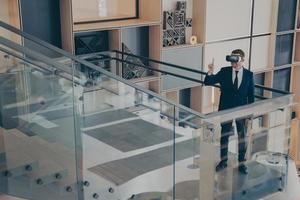 CEO of gaming company testing prototype of VR headset while walking around office center lobby photo