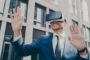Professional impressed worker standing outside alone and using VR glasses to visualize projects photo
