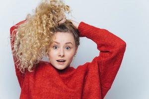 Emotional surprised female strares at camera with unexpected look, keeps hair in pony tail, expresses surprisment, isolated over white studio background. Its unbelievable Amazement and shock photo