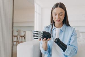 Disabled young woman is assembling bionic arm with hand. Prosthesis is connecting in wrist joint. photo