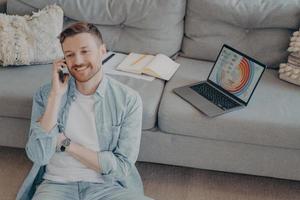 Happy young man calling family to inform about receiving promotion photo