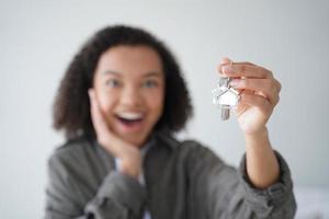 Happy girl tenant show keys of new house. Close-up of hand with home key. Real estate rental service photo