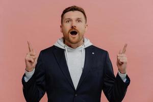 Shocked ginger man pointing up with index fingers with wow face expression photo