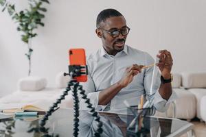 Video call on phone. Afro freelancer has online brainstorm. Happy man shows paperwork with data. photo