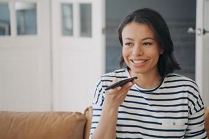 Female sends voice message by smartphone, uses speaker phone, enjoying online communication at home photo