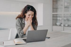 Excited young businesswoman has video call on laptop. Corporate internet session. photo