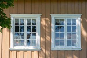 Two white windows sitting side by side on a yellow, wood paneled wall. photo