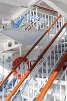 White stairs and a wooden railing between the decks of a cruise ship. photo