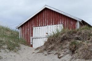un cobertizo para botes rojo de madera en la playa en grense jakobselv, noruega. foto
