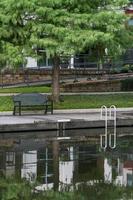 los bosques, texas, ee.uu. - 11 de julio de 2021. un banco verde bajo un árbol a lo largo del canal. foto