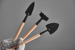 Hand in a glove holding gardening tools isolated on gray background. photo