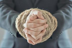 Business man pulling and bond tied with rope concept. Business hands are tied photo