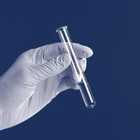 Hand holding liquid in test tube close up isolated on a blue background. photo