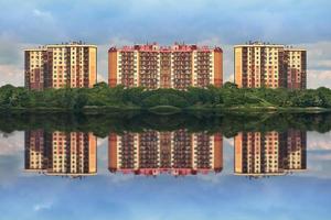 New urban area surrounded by a green Park. Symmetrical new buildings are reflected in the river. photo