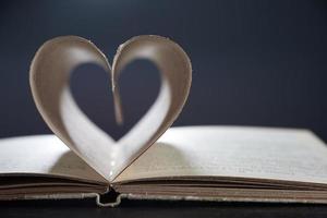 A Romance Novel. Open book close. The pages are arranged in a heart shape on a gray background in a blur. Photo with copy space.