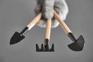 Hand in a glove holding gardening tools isolated on gray background. The background in blur photo