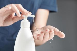 Female hands using hand sanitizer gel pump dispenser. photo