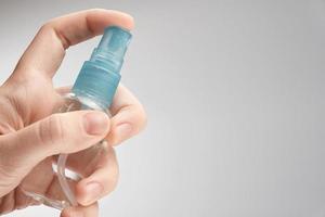 Woman hand holding cosmetics bottle isolated on grey background. Photo with copy space.