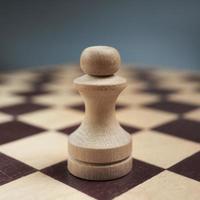 One white pawn close-up on a chessboard on a gray background. Background in blur. photo