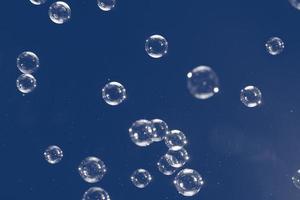 Flying soap bubbles isolated on blue background. Abstract background. photo