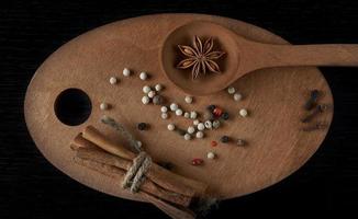 Set of wooden utensils with star anise pepper cinnamon isolated on dark background. photo