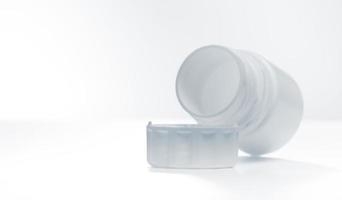 botella de plástico blanco para vitaminas situadas cerca de la tapa horizontalmente aisladas sobre fondo blanco. foto con espacio de copia.