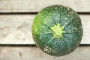 Green round zucchini isolated on wooden background. photo