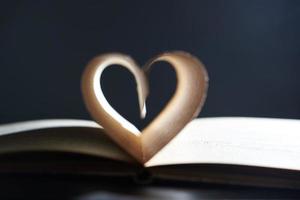 una novela romántica. libro abierto primer plano enfoque suave. las páginas están dispuestas en forma de corazón sobre un fondo gris en un desenfoque. foto