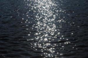 Selective focus of sparkling water with wave motion reflecting the bright sunlight with a very soft bokeh photo