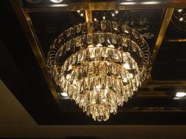 A large crystal chandelier sparkling golden yellow on the ceiling of any room in your home or restaurant. photo