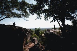 silueta de gran angular del paisaje en los acantilados y árboles con vistas al campo de abajo, con turistas parados a sus espaldas, el concepto de turismo de relajación natural. foto