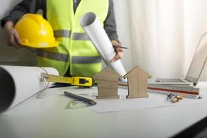 Two colleagues discussing data working and tablet, laptop with on on architectural project at construction site at desk in office photo